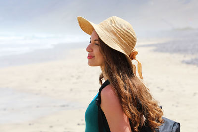 Portrait of woman wearing hat while standing on beach