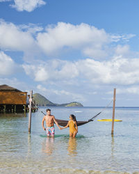 Rear view of woman standing in sea against sky