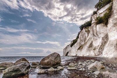 Rock formation on beach against sky