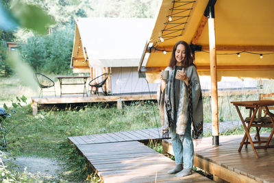 Portrait of young woman standing against building