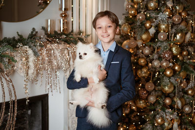 Portrait of a boy and a dog on the background of a christmas tree