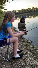 Side view of girl sitting on lake