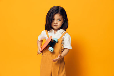 Portrait of young woman standing against yellow background