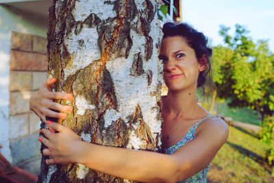 Portrait of woman holding tree trunk