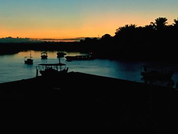 Silhouette boats in sea against clear sky during sunset