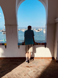 Rear view of man looking at sea against sky