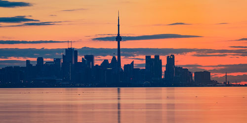 Silhouette buildings in city against sky during sunset