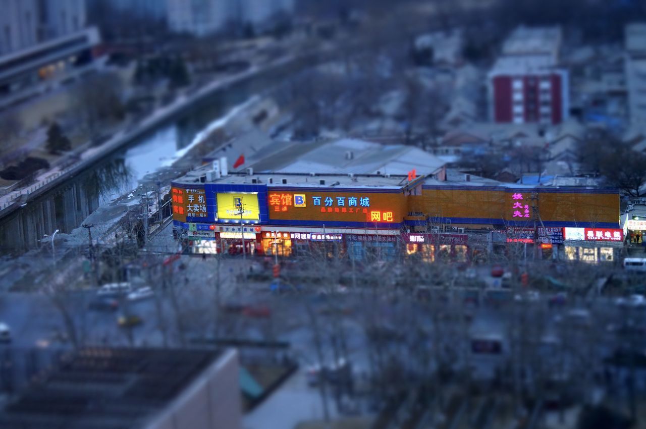 HIGH ANGLE VIEW OF ILLUMINATED CARS ON CITY IN BACKGROUND