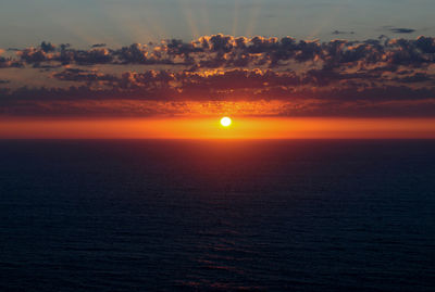 Scenic view of sea against dramatic sky during sunset