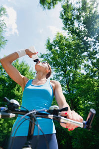 Woman drinking water while riding bicycle in park