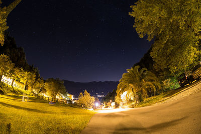 Road by trees against sky at night