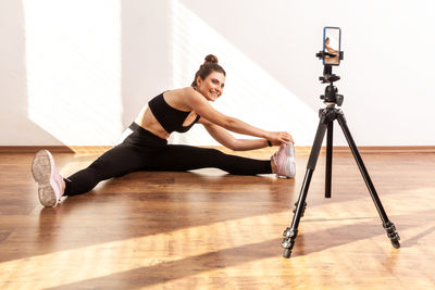 Full length of woman sitting on hardwood floor