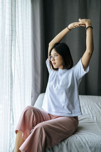 Young woman sitting on bed at home