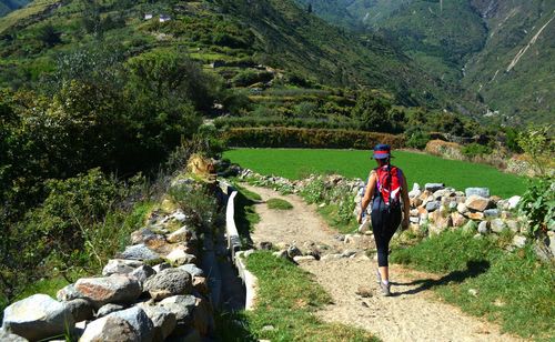 Rear view of woman walking on landscape against mountain