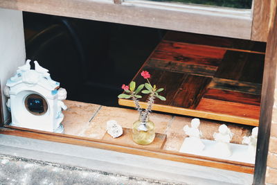 High angle view of flower vase by figurines and alarm clock on window sill