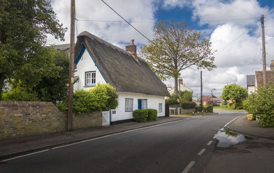 Road by buildings in city against sky