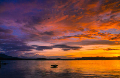 Scenic view of dramatic sky over lake during sunset