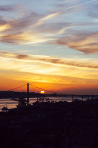 Sunset overlooking lisbon's baixa and 25 april bridge on the tagus river, portugal