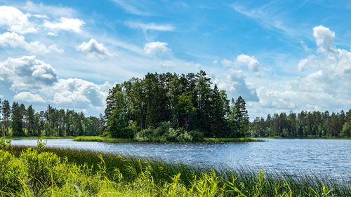 Scenic view of lake with island by trees against sky