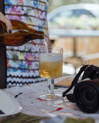 Cropped image of woman pouring beer in glass on table