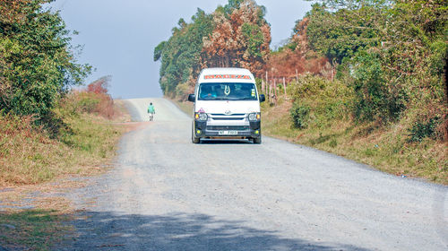 Car on dirt road by trees