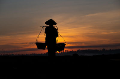 Silhouette person on field against sky during sunset