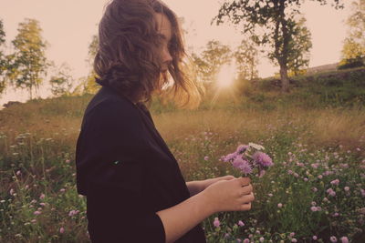 Woman holding purple flowers on field