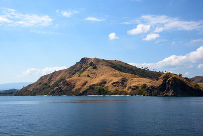 Scenic view of sea by mountain against sky