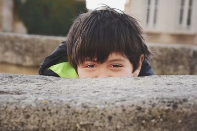 Close-up portrait of boy by retaining wall