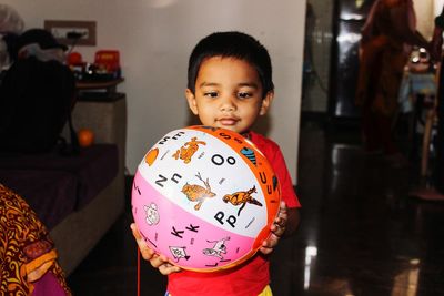 Cute boy holding ball while standing at home