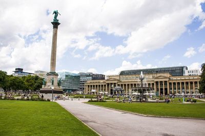 Statue in city against cloudy sky