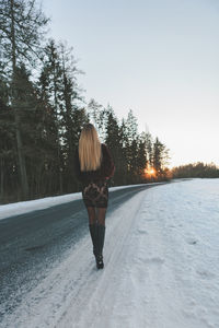 Rear view of woman standing on snow covered road