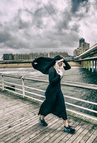 Full length of woman standing on bridge against sky