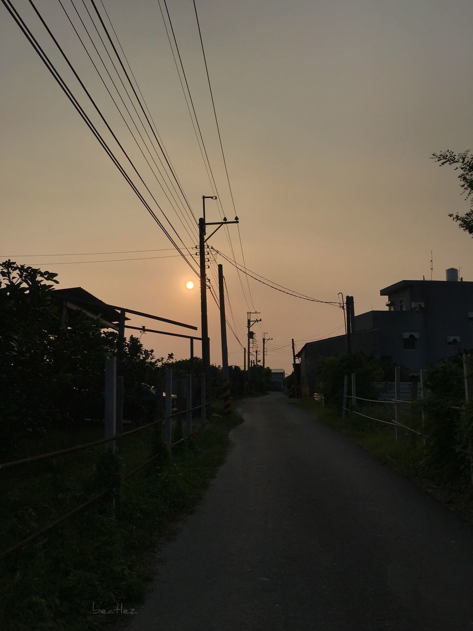 sunset, the way forward, street, architecture, built structure, building exterior, empty, sun, road, clear sky, long, electricity pylon, narrow, diminishing perspective, orange color, power line, sky, empty road, no people, tranquil scene