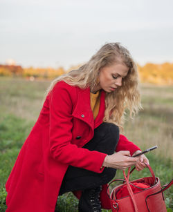 Young woman with red umbrella standing on field