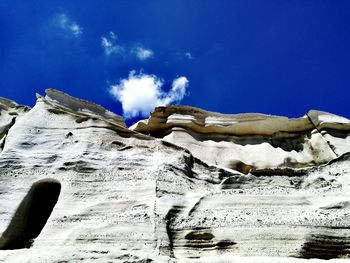 Low angle view of snow covered mountain against blue sky