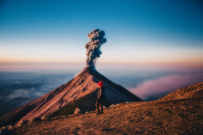 Woman standing against volcanic landscape during sunset