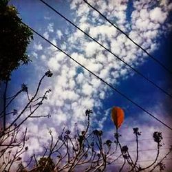 Low angle view of power lines against cloudy sky