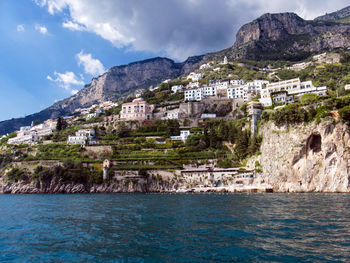 Buildings by sea against sky