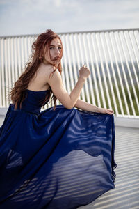 Portrait of woman in dress sitting on bridge 