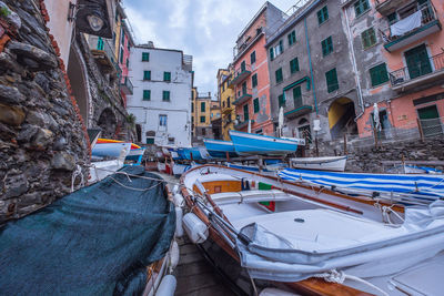 Boats moored on street by buildings in city