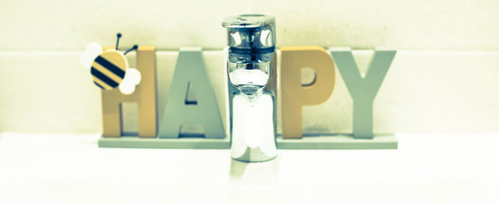 Close-up of glasses on table against wall at home