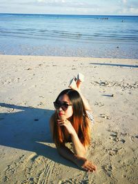 Portrait of woman in sunglasses lying at beach