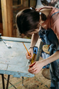 Close up view of hardworking professional carpenter woman hands working with ruler, making marks on