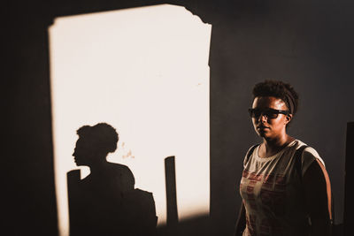 Woman in eyeglasses standing by shadow at home