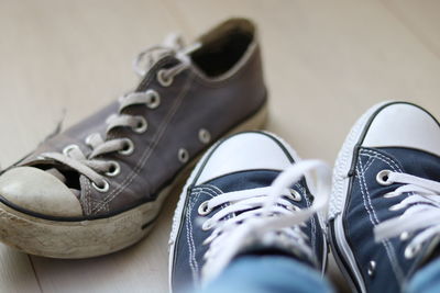 Low section of person wearing canvas shoes on hardwood floor