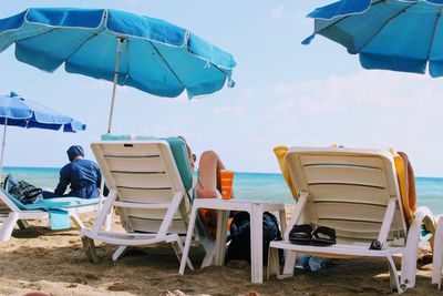 Lounge chairs on beach against sky