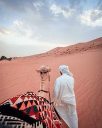 Rear view of people walking in desert against sky