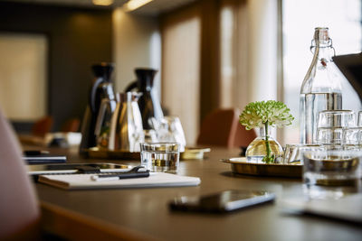 Digital tablet with diary and drinking glass at conference table in office