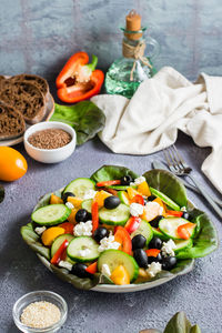 Greek salad of tomatoes, cucumbers, peppers, olives, lettuce and cheese on a plate on the table. 